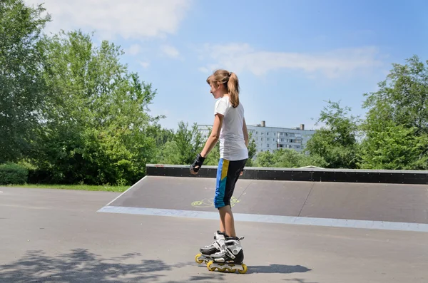 Mladá dívka na kolečkových bruslích ve skate parku — Stock fotografie