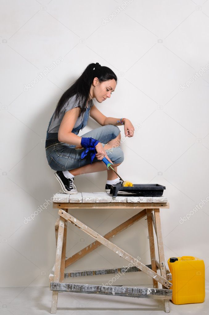 Handy young woman painting her hoause