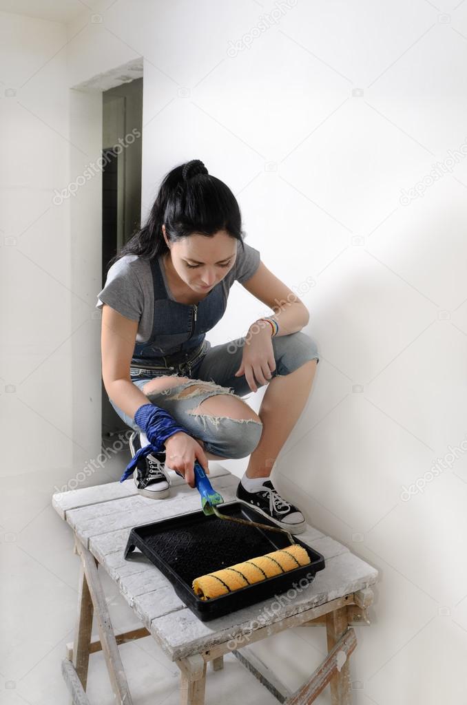 Capable young woman painting a wall