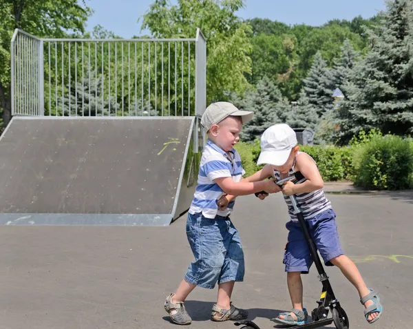 Two young boys fighting over a scooter — Stock Photo, Image