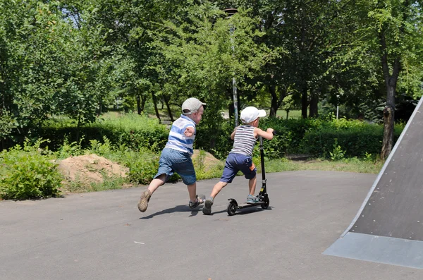 Two young boys playing with a scooter — Stock Photo, Image