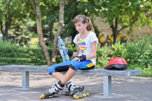 Tonårsflicka dricksvatten under skridskoåkning paus — Stockfoto