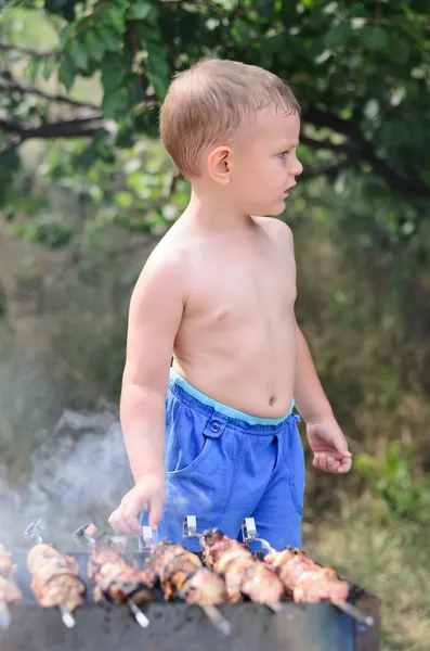 Young boy grilling kebabs on a barbecue — Stock Photo, Image