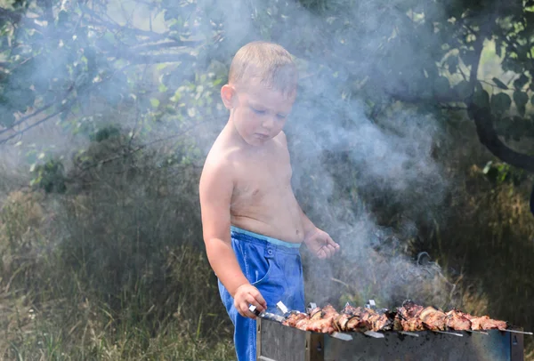 Young shirtless boy cooking at a barbecue — Stock Photo, Image