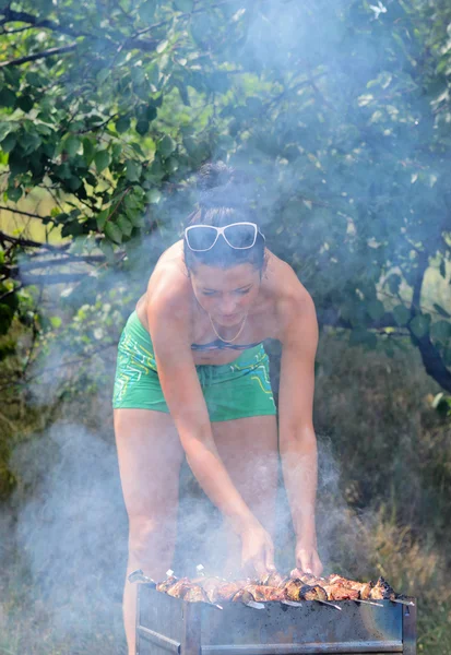 Jonge vrouw koken van vlees op een barbecue — Stockfoto