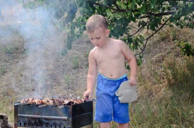 küçük çocuk kebap ateşte çevirerek