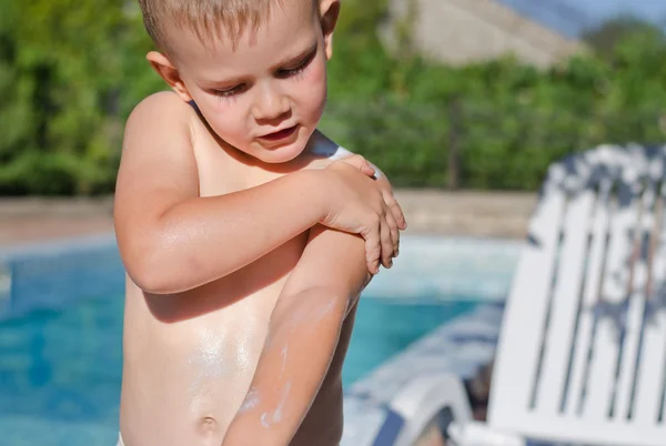 Ung pojke noggrant tillämpa solskyddsmedel — Stockfoto