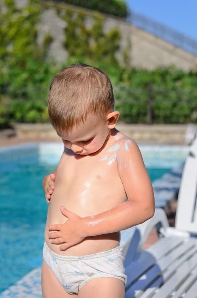 Liten pojke gnugga solskyddsmedel på hans hud — Stockfoto