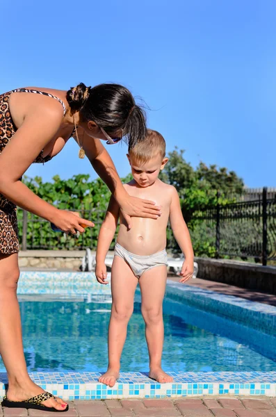 Jonge moeder zonnebrandmiddel toepast haar zoon — Stockfoto