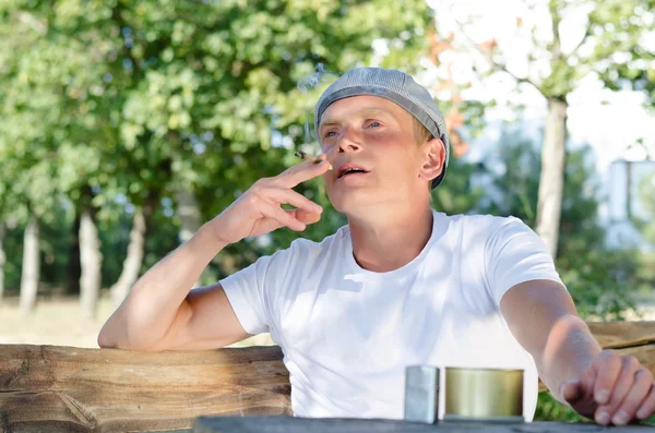 Man sitting outdoors smoking — Stock Photo, Image