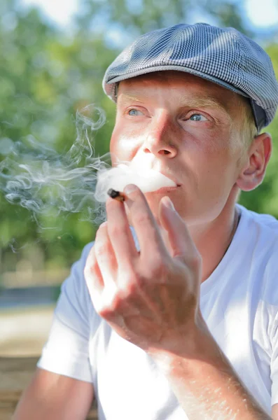 Homem soprando em um cigarro caseiro — Fotografia de Stock