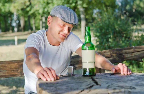 Mellow drunk smiling at his bottle of alcohol — Stock Photo, Image