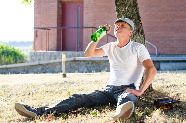 Hombre bebiendo alcohol de una botella — Foto de Stock