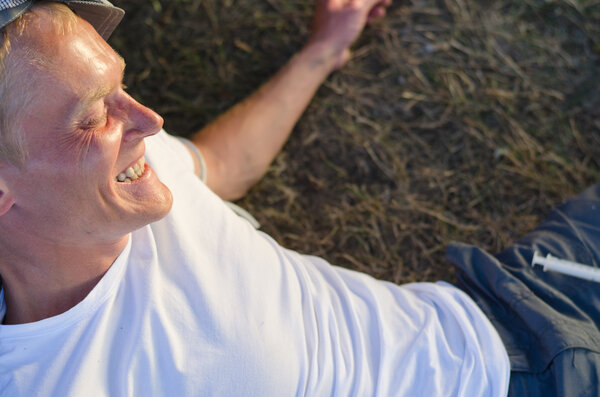 Addicted man laughing lying down on grass