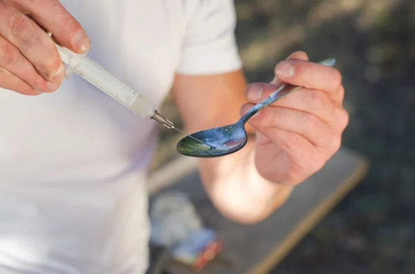 Drug user filling a syringe with crack cocaine — Stock Photo, Image