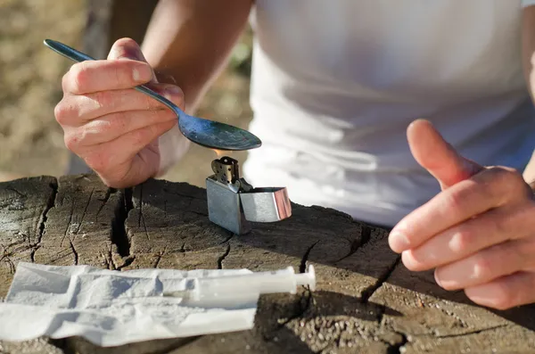 Hands of an addicted man while heating heroin — Stock Photo, Image