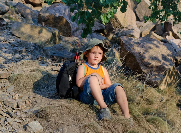Little boy sitting on the ground at the mountains — Stock Photo, Image