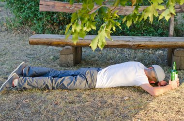 Drunk man sleeping it off in a park clipart