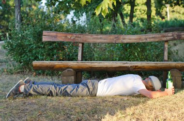 Drunk man sleeping it off in a park clipart