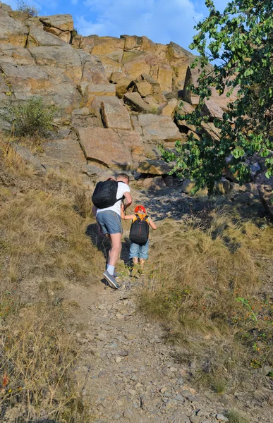 Man helping his son to hike on a rough area — Stock Photo, Image