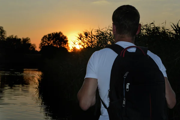 Backpacker de pé assistindo o pôr do sol — Fotografia de Stock