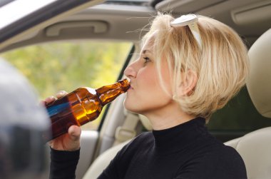 Young female driver drinking bear in the car clipart