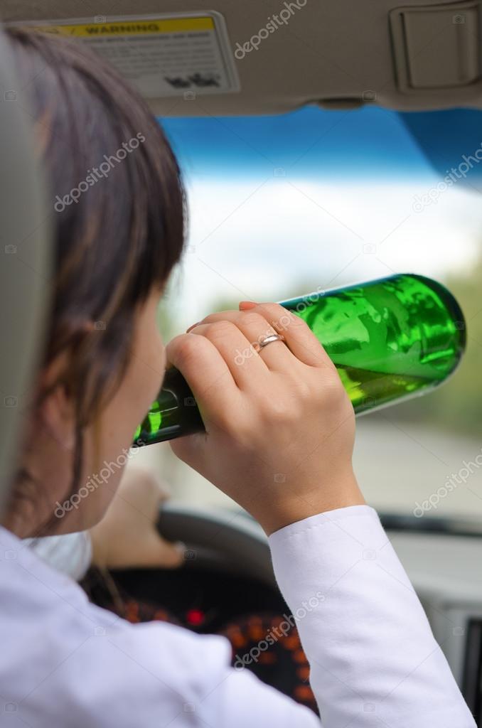 Woman driver drinking while driving on a road