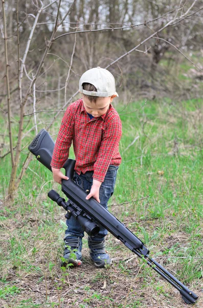 Kleine jongen een sportieve geweer sjouwen — Stockfoto