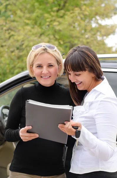 Duas mulheres assinando um contrato para comprar um carro — Fotografia de Stock