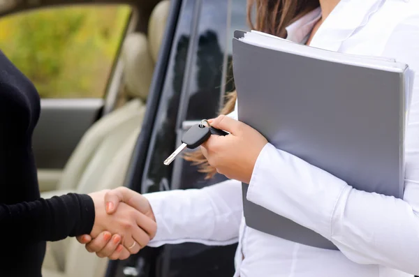 Vendedora vendiendo un coche y dándole la mano — Foto de Stock