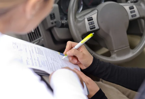 Autofahrerin unterschreibt ein juristisches Dokument — Stockfoto