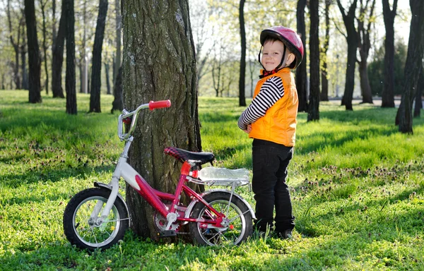 Liten pojke stående flinande tillsammans med sin cykel — Stockfoto