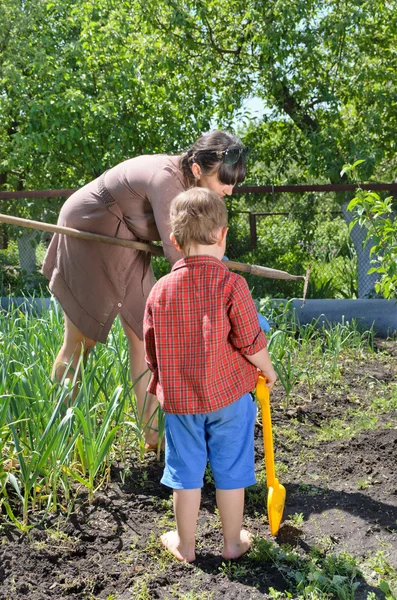 Mały chłopiec obserwując jego matka w ogrodzie — Zdjęcie stockowe