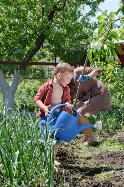 Kleine jongen te helpen mama water de moestuin — Stockfoto