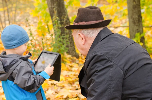 Niño usando una tableta PC con el abuelo viendo —  Fotos de Stock