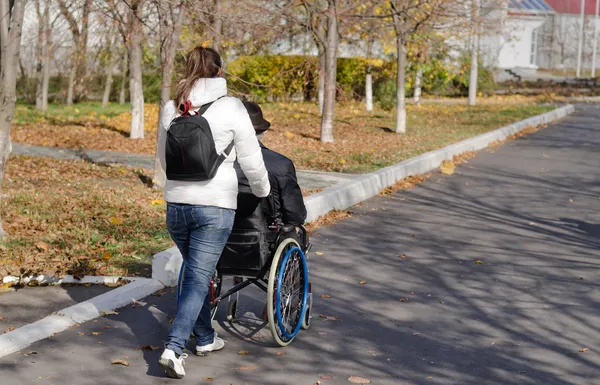 Opiekun biorąc niepełnosprawny mężczyzna na spacer — Zdjęcie stockowe
