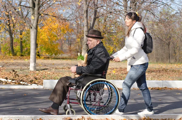 Mujer tomando un anciano discapacitado hombre compras —  Fotos de Stock