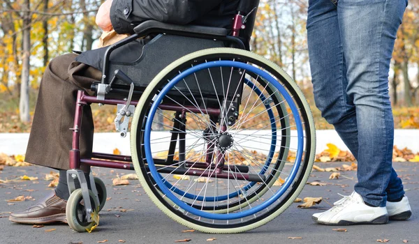 Disabled man in a wheelchair with a carer — Stock Photo, Image