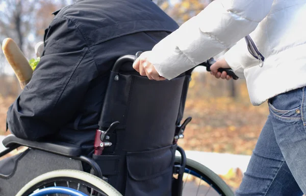 Frau schubst behinderten Mann im Rollstuhl — Stockfoto