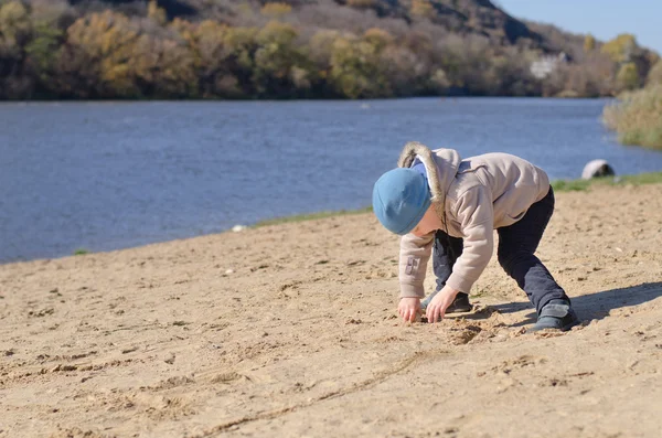 Маленький мальчик рисует на песке — стоковое фото