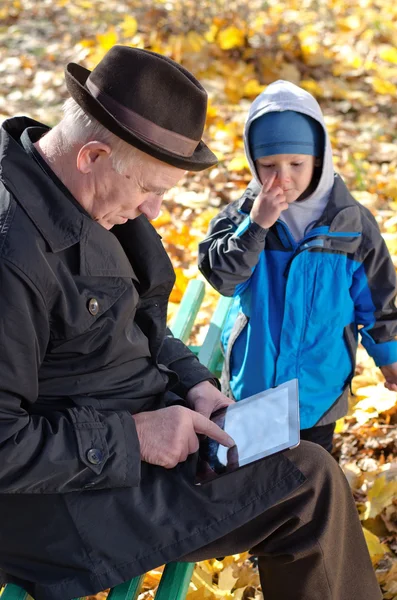 Grandfather using a tablet watched by his grandson — Stock Photo, Image