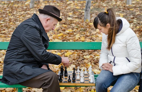 Älterer Mann streitet sich beim Schachspiel mit Frau auf hölzerner Parkbank — Stockfoto