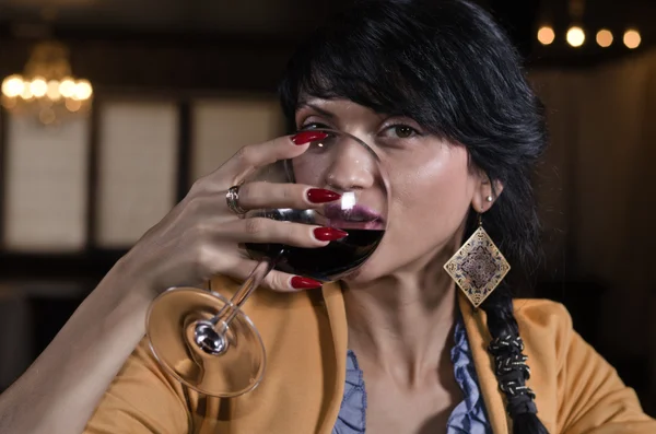 Mulher bonita bebendo vinho tinto em um bar — Fotografia de Stock