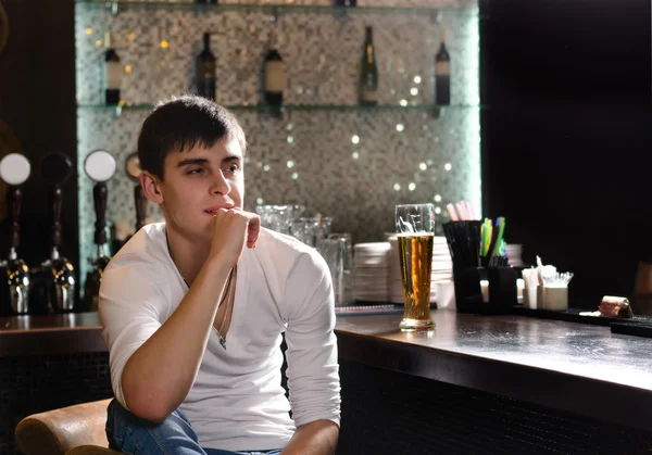 Zadumany młodzieniec siedzący myślenia w barzedoordachte jongeman vergadering denken in een bar — Stockfoto