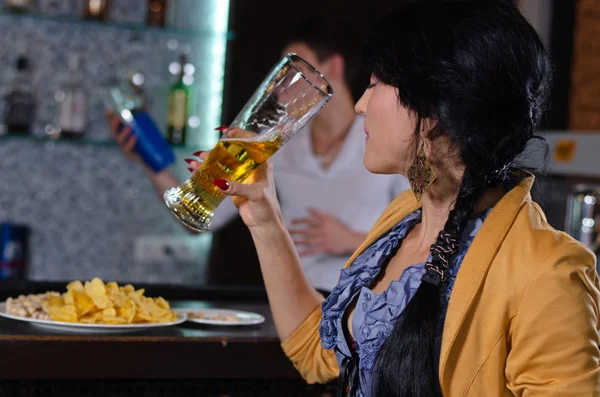 Mujer joven disfrutando de una cerveza en el bar — Foto de Stock