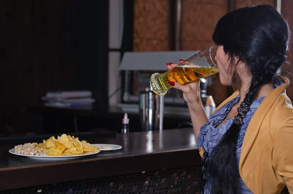 Frau verschluckt ein Bier an der Bar — Stockfoto