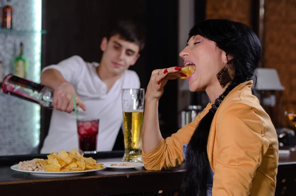 Junge Frau genießt einen Imbiss an der Bar — Stockfoto