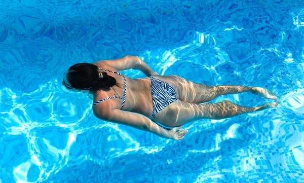 Donna che nuota in una piscina blu turchese — Foto Stock