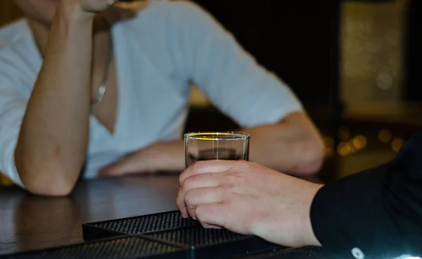 Mano masculina sosteniendo un vaso en un mostrador de bar — Foto de Stock