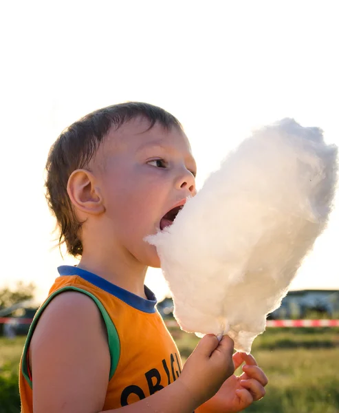 Young boy eating a stick of cotton candy — Stock Photo, Image